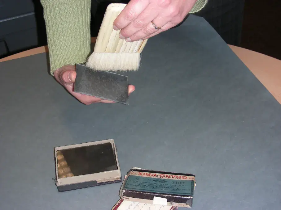 Une personne brosse une photographie sur plaque de verre.